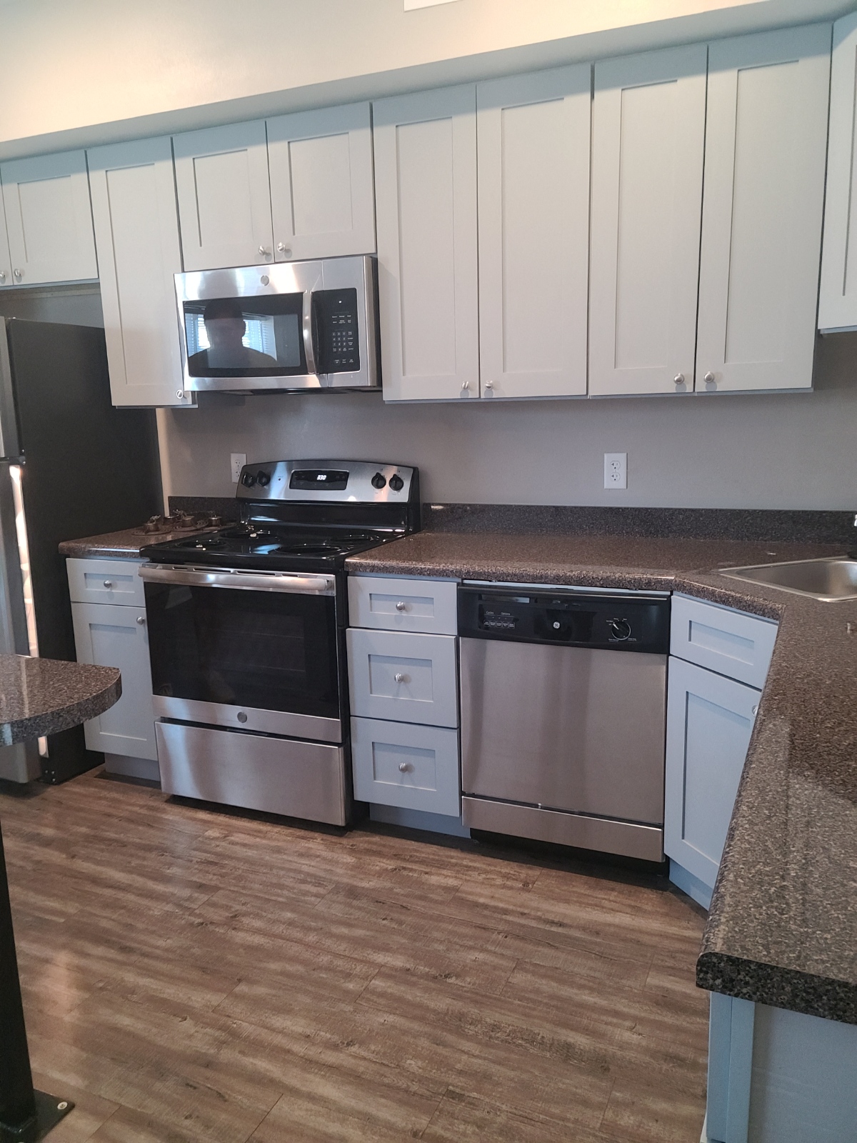 A kitchen with a black refrigerator and stainless steel appliances.